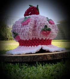 a knitted strawberry hat sitting on top of a tree stump