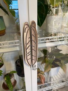 a door handle on the side of a white cabinet with potted plants behind it