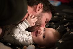 a man holding a baby while laying on top of it's back with his mouth open