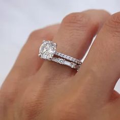 a woman's hand with a diamond ring and two wedding bands on it,