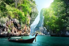 a boat floating on top of a body of water next to tall rocks and cliffs