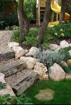 an outdoor play area with rocks, grass and trees