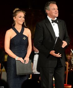 a man in a tuxedo standing next to a woman in a black dress