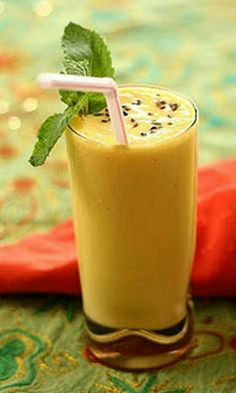 a smoothie in a tall glass with a straw and mint garnish on top