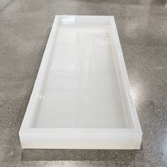 an empty white box sitting on top of a cement floor