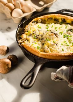 a pizza sitting on top of a pan covered in cheese and mushrooms next to eggs