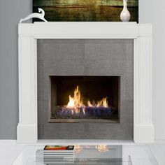 a fire place in a living room with a painting on the wall and a vase