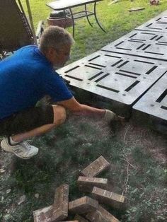 a man kneeling down on the ground next to blocks of wood