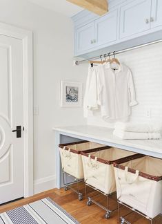 an organized closet with clothes hanging on hooks and storage bins under the counter top