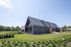 the house is made out of black bricks and has an open lawn area in front of it