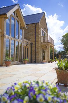 a large brick house with lots of windows and flowers in the foreground on a sunny day