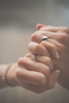 two hands are holding each other with rings on their fingers and one has a diamond ring