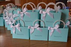 several small blue boxes with white bows and pearls on them, sitting on a table