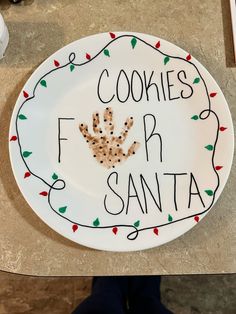 a white plate with cookies for santa written on it and a handprinted cookie