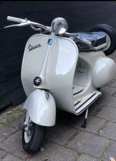 a white scooter parked next to a black wall