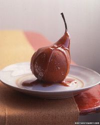 a pear covered in caramel sauce sitting on a plate next to a table cloth