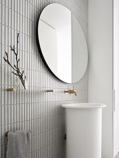 a white sink sitting under a round mirror