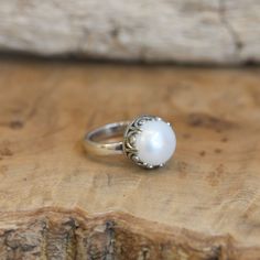 What a fun and elegant - Big Pearl Ring. With a stunning, creamy white, AAA mabe pearl at the center, our new Majestic Pearl Ring feels magic. The detailed sterling silver Gallery Wire Bezel against the big, lustrous, creamy white freshwater mabe pearl is perfect and unique - offering you a unique and different pearl ring. We only wish we had more of these AAA grade freshwater Mabe Pearls. Choose your size in the drop-down below - while they last. AAA, White Freshwater Pearl measures 12 - 12.5mm White Sterling Silver Pearl Ring Gift, Classic White Pearl Ring With Drop Detail, White Pearl Drop Ring Jewelry, White Pearl Drop Ring For Anniversary, Elegant Handmade Pearl Promise Ring, Elegant 925 Stamped Pearl Promise Ring, Heirloom White Pearl Ring, White Sterling Silver Pearl Ring, Pearl White Sterling Silver Ring For Gift