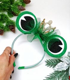 someone is making an eyeball headband out of green mesh and some pine cones