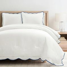 a bed with white sheets and blue trim