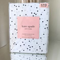 a white and black polka dot print sheet with a pink tag on it that says kate spade new york