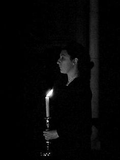 a woman holding a lit candle in the dark