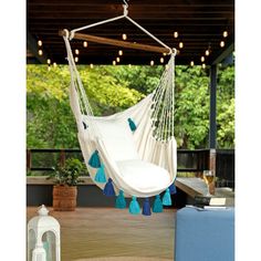 a white hammock hanging from a ceiling with blue tassels on it