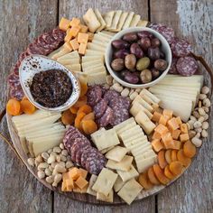 an assortment of cheeses, nuts and meats on a platter with dip