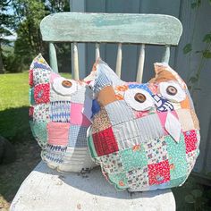 two stuffed owls sitting on top of a wooden chair covered in patchwork and fabric