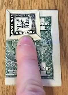 a finger is pointing at a dollar bill