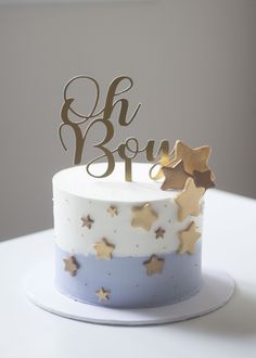 a white and blue cake with gold stars on it's top that says oh boy