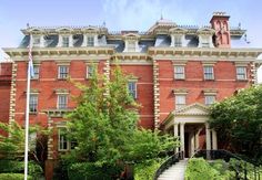 an old red brick building with stairs leading up to the front door and trees on either side