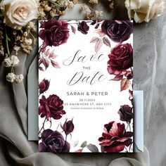 an elegant floral save the date card on top of a table with flowers and greenery