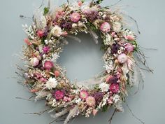 a wreath made out of dried flowers on a gray background with white and pink blooms