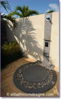 an outdoor shower in the middle of a patio with palm trees and blue sky behind it