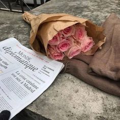 a bouquet of pink roses sitting on top of a newspaper