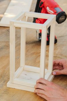 someone is working on a small wooden object with woodworking tools in the back ground