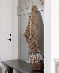 a towel hanging on a coat rack next to a basket with dried flowers in it