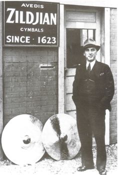 a man standing in front of a building with two large rolls of paper on the ground