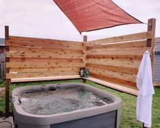 an outdoor hot tub in the backyard next to a wooden fence with a towel hanging on it