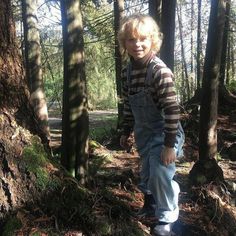 a young boy standing in the middle of a forest