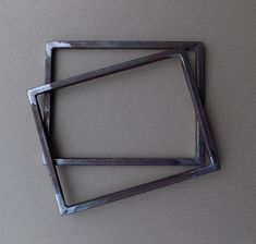 three square metal objects sitting on top of a white surface with no one around them