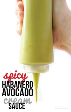 a hand holding a green sauce bottle with the words spicy habanero avocado cream sauce on it