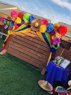 a colorful display on the grass in front of a wooden structure with paper flowers and fan decorations