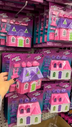 a person holding a toy in front of a display of barbie's house toys