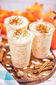 three glasses filled with pumpkin spice latte on a wooden tray