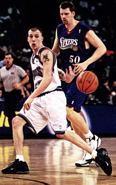 two men are playing basketball on a court with people watching them from the sidelines