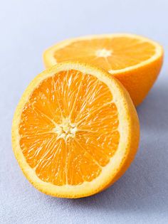 two oranges cut in half on a blue surface