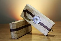 two small wooden boxes sitting on top of a table next to each other, one with a button in the middle