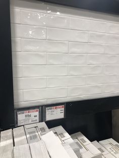 stacks of newspapers are stacked on top of each other in front of a white brick wall